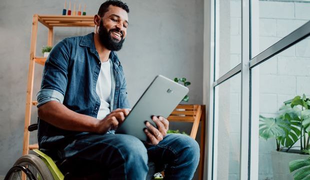 Man in wheelchair in apartment looking at tablet