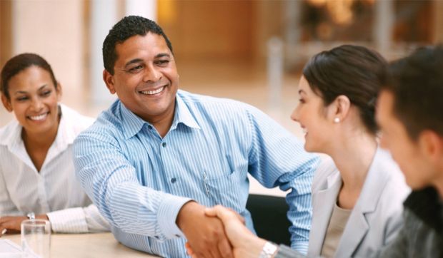 Man shaking hands with a woman as two others look on