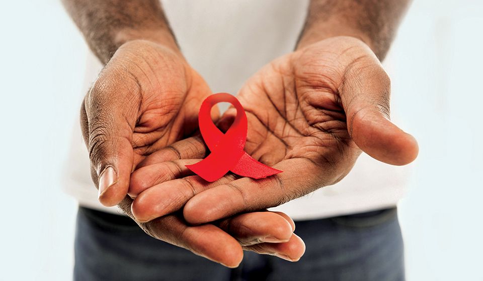 Close up of a man's hands held one on top of the other, a red ribbon in his palms