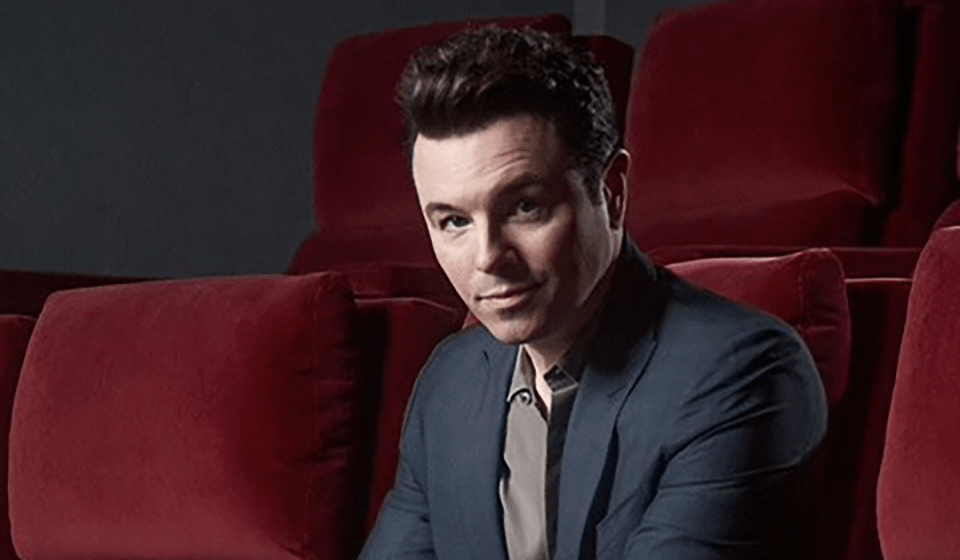 Headshot of Seth MacFarlane, sitting in a row of red theater chairs