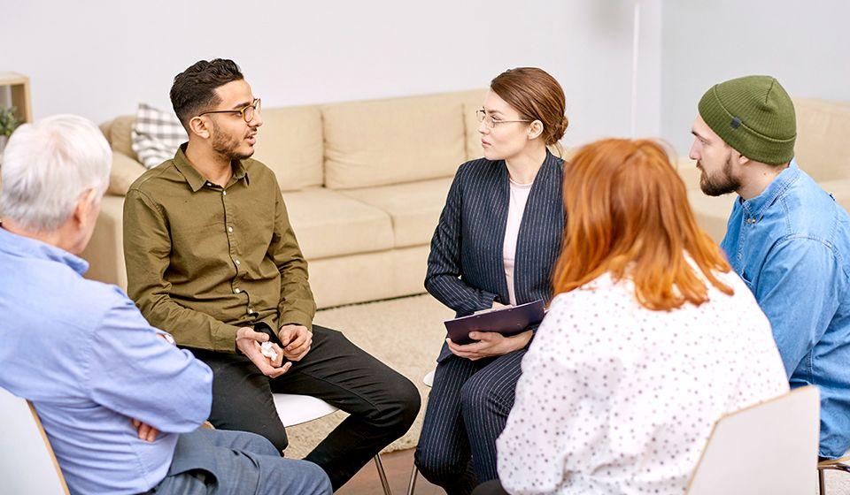 A group of men and women sit in a circle having a conversation